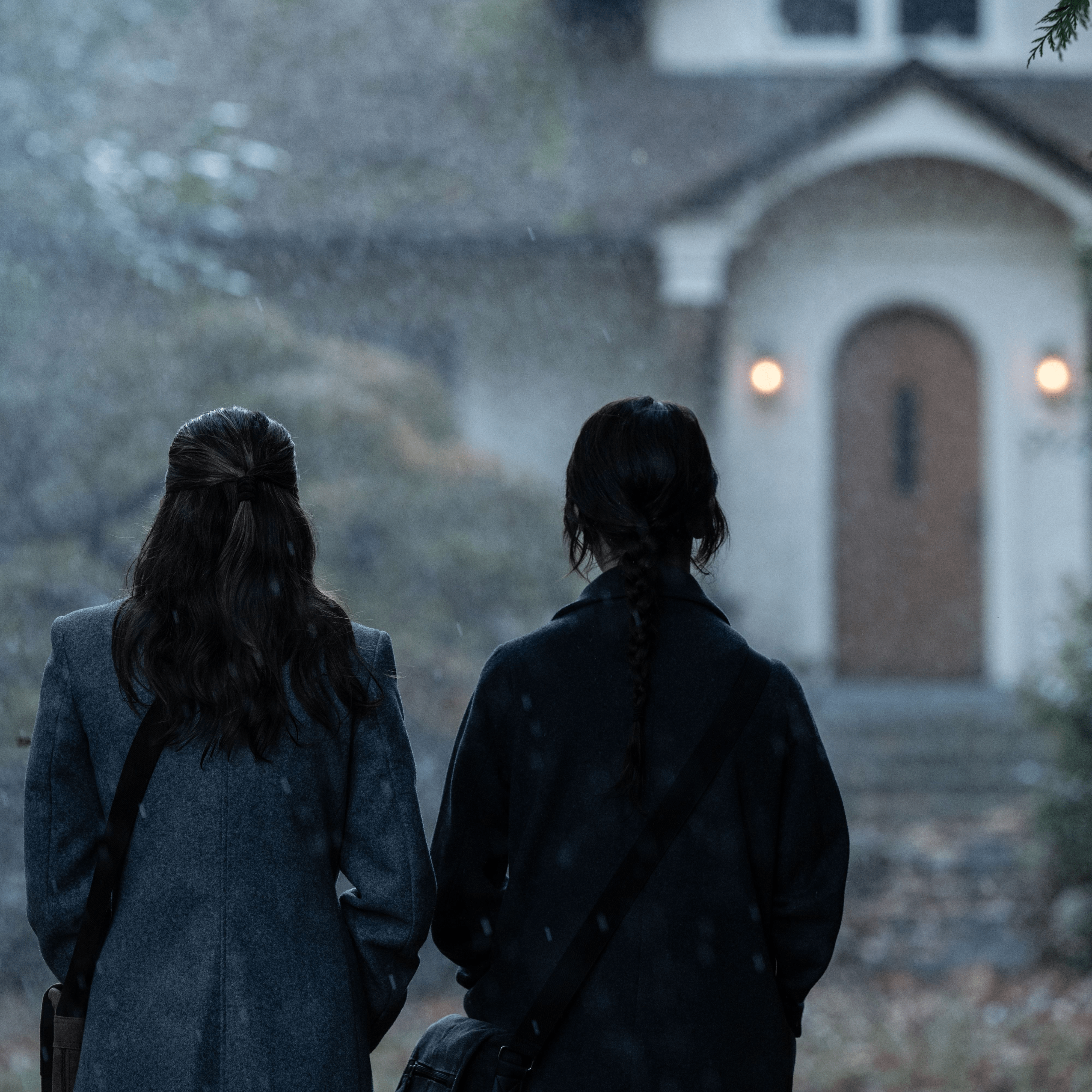 two girls with their backs to us looking at a house